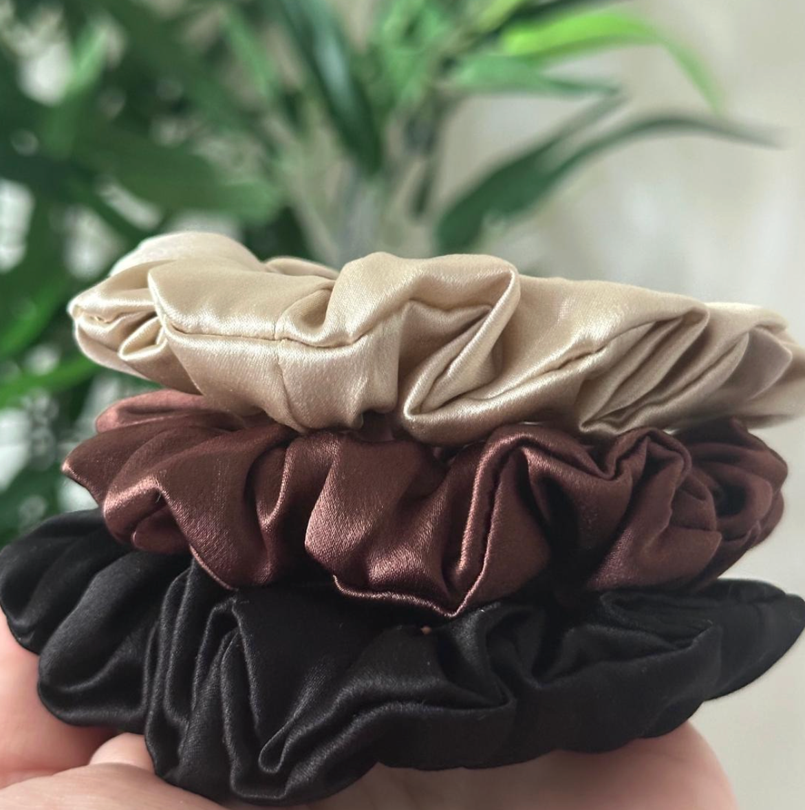 Pile de trois chouchous en soie : creamy beige, marron chocolat et noir