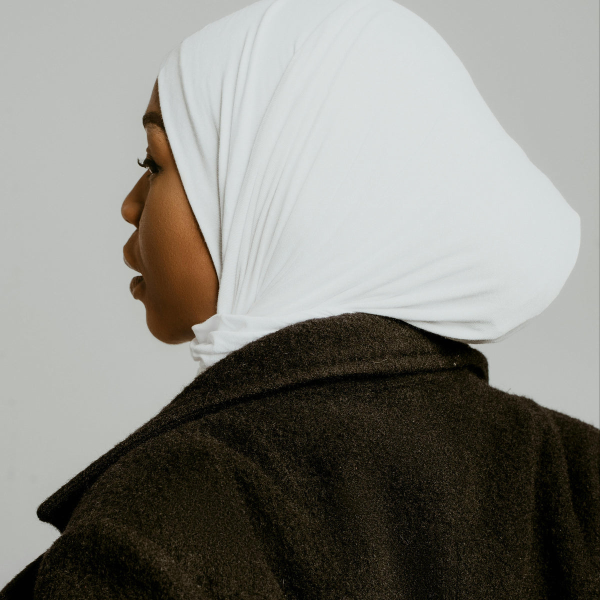Femme de profil portant un bonnet sous-voile blanc